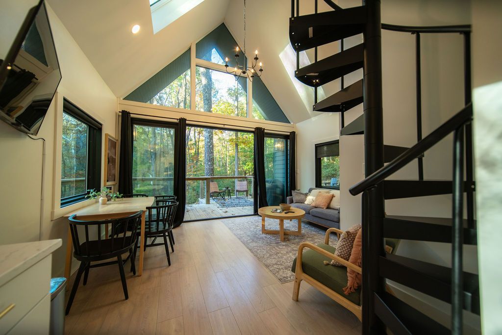 A spacious loft with a high ceiling, a dining area, a sofa, and a staircase.