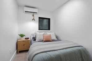Un dormitorio con cama, mesita de noche y ventana.
