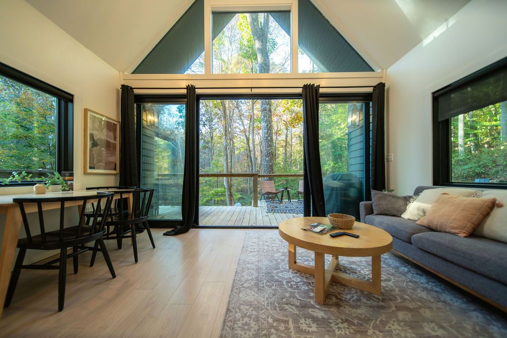 A modern interior with a dining area, a sofa, and a large sliding glass door leading to a deck.