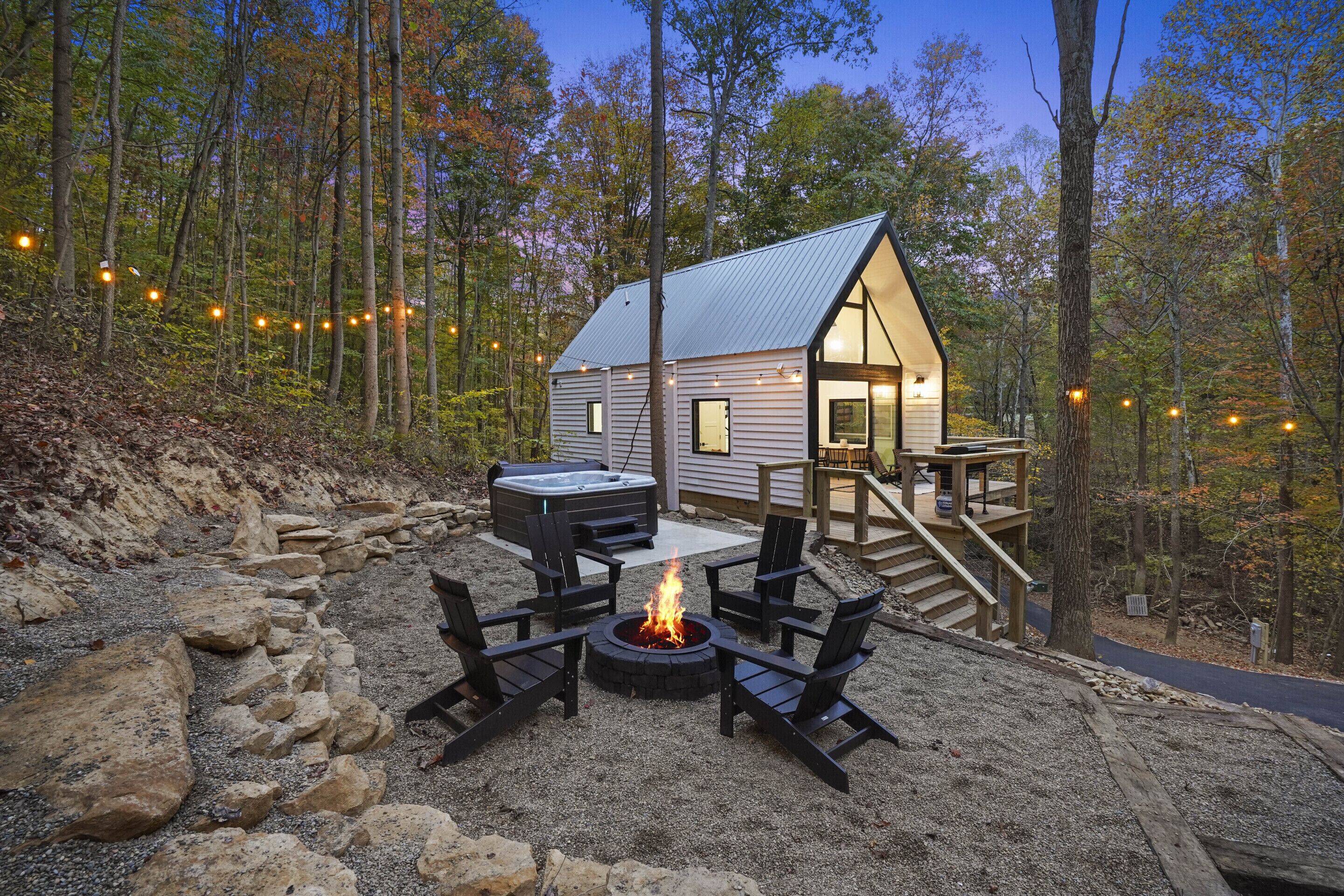 Eine Hütte mit Terrasse, Whirlpool und Feuerstelle, umgeben von Steinen.