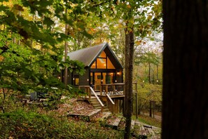 A cabin with a deck, surrounded by trees. - Rocky Hollow | Hocking Hills, Lush Cabin, Hot Tub (Rockbridge)