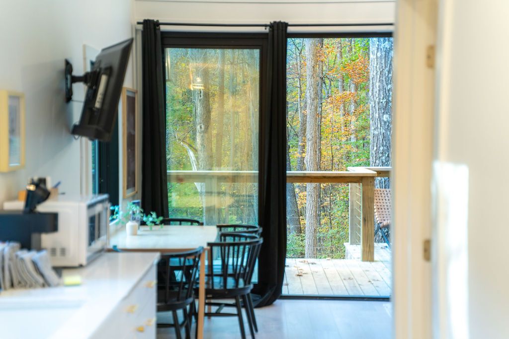 Cozinha moderna com área de refeições, janelas amplas e vista para uma floresta.