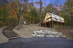 Una cabaña con una terraza de madera y un sendero de piedra que la conduce.