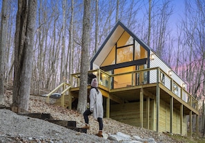 A cabin with a wooden exterior, large windows, and a balcony.