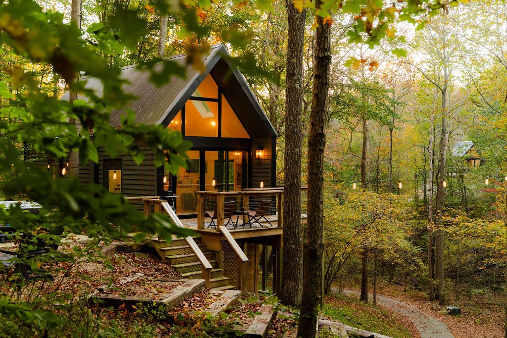 A cabin with a deck, surrounded by trees.