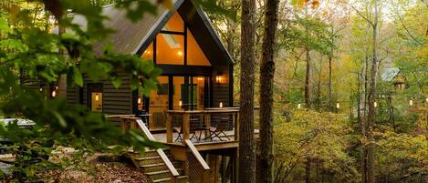 A cabin with a deck, surrounded by trees.
