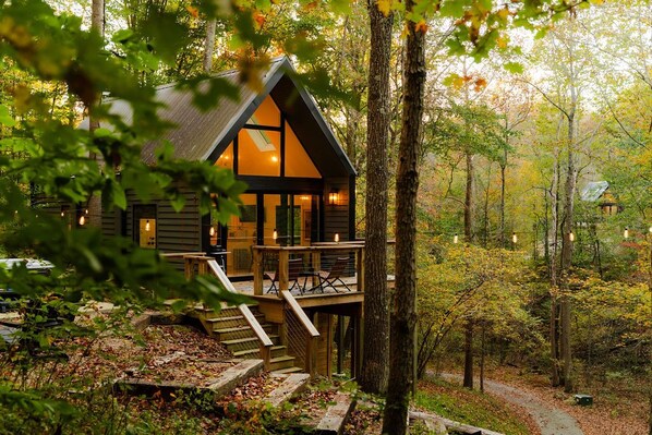 A cabin with a deck, surrounded by trees. - Rocky Hollow | Hocking Hills, Lush Cabin, Hot Tub (Rockbridge)