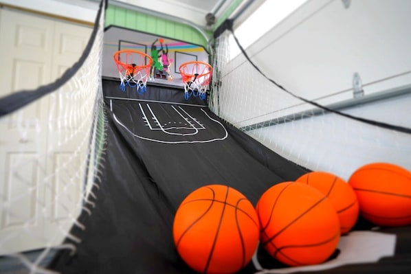 Una cancha de baloncesto en miniatura con una red, dos aros y tres balones de baloncesto.