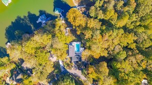 Luchtbeeld van een bezit met een zwembad, omringd door dichte bomen en een klein steiger.