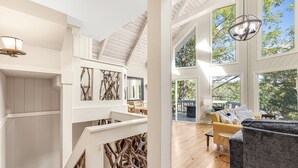 Een ruime woonkamer met een hoge nok, grote ramen en een moderne haard.