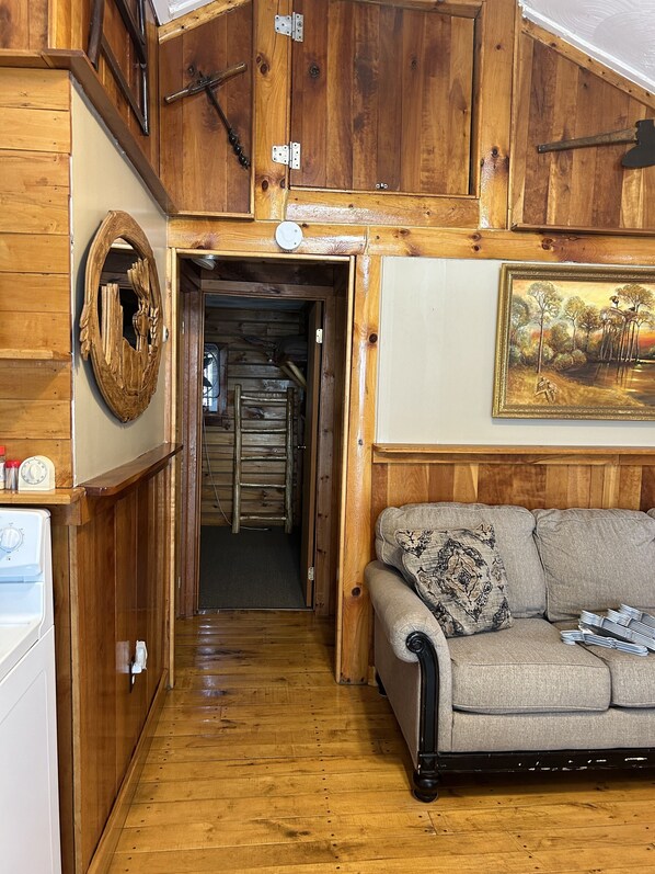 A wooden interior with a sofa, a wooden door, and a painting on the wall.