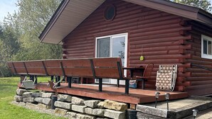 A wooden cabin with a porch, stone steps, and outdoor seating.