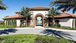 A gated entrance with a central archway, flanked by palm trees and a well-maintained lawn. - Solterra Resort-7 Bedrooms 5.5 Bath Pool/Spa-Clubhouse/Lazy River-Near Disney (Davenport)