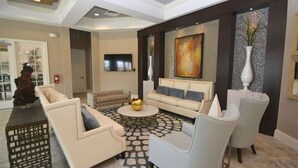 A modern living room with a sofa, armchairs, a coffee table, and a TV. - Solterra Resort-7 Bedrooms 5.5 Bath Pool/Spa-Clubhouse/Lazy River-Near Disney (Davenport)