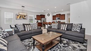 A modern living room with two grey sofas, a wooden coffee table, and a ceiling fan. - Solterra Resort-7 Bedrooms 5.5 Bath Pool/Spa-Clubhouse/Lazy River-Near Disney (Davenport)