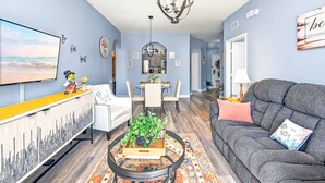 A living room with a sofa, coffee table, TV, and dining area. - Disney | Condo | Windsor Hills | Water Park (Kissimmee)