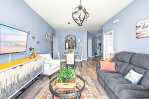 A living room with a sofa, coffee table, TV, and dining area.
