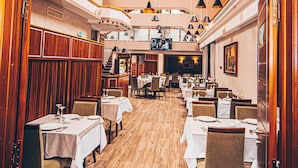 L’intérieur d’un restaurant, avec plusieurs tables, des chaises et un plancher en bois.