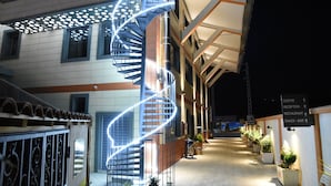 Un bâtiment moderne doté d’un escalier en colimaçon, de plantes en pot et de panneaux indiquant la réception, le restaurant et le bar à collations.