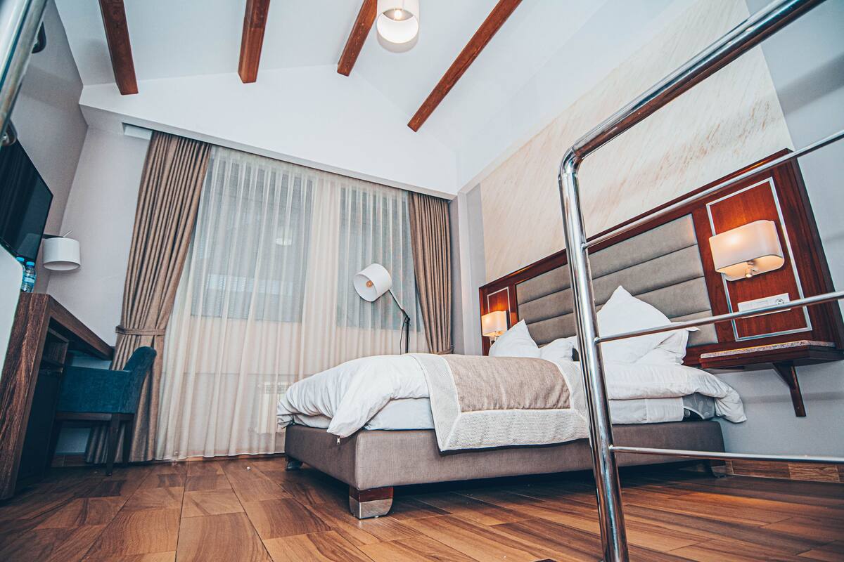 A modern hotel room with a bed, a desk, and a chair.