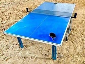 A ping pong table with a blue playing surface and a white net, set on a sandy surface. - Mas des Bécasses in Provence 22 pax (Arles)
