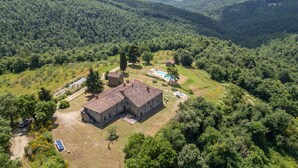 An aerial view of a stone building with a tiled roof, surrounded by lush greenery and hills. - 6 bedroom awesome home in Anghiari (Anghiari)