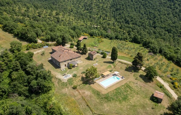 Vista aérea de una propiedad rural con una casa grande, piscina y abundante vegetación.