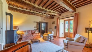 A cozy living room with a fireplace, a sofa, a chair, and a glass coffee table. - 6 bedroom awesome home in Anghiari (Anghiari)