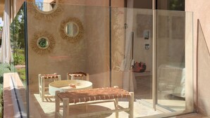 A modern outdoor seating area with a glass partition, two round mirrors, and a small table. - Dar Lala Mama (Marrakech)