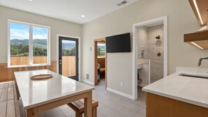 A modern kitchen with a large window, wooden flooring, and a built-in sink. - Brand New Luxury Beach Home w Hot Tub & Sauna (Rockaway Beach)