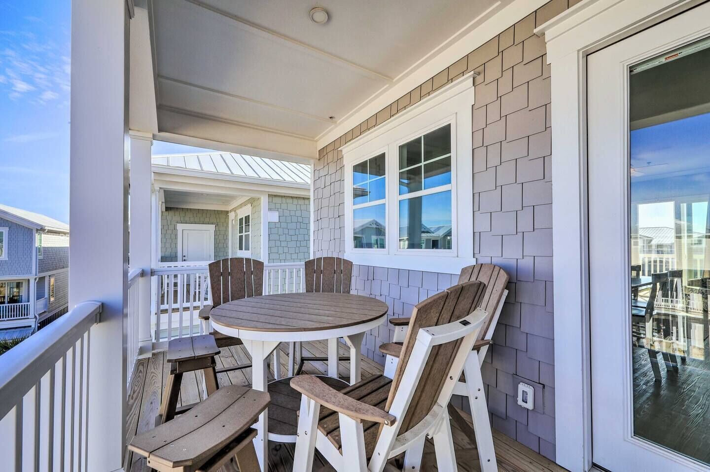 A covered outdoor patio with a round wooden table and four chairs.