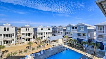 A beachfront hotel with multiple-story buildings, a swimming pool, and outdoor seating areas.