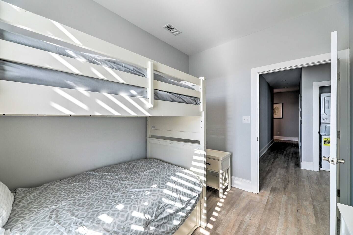 A bedroom with a bunk bed, a bedside table, and a wardrobe.