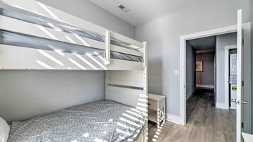 A bedroom with a bunk bed, a bedside table, and a wardrobe.