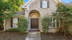 A brick house with a front door, a small porch, and a window with shutters. - Serene Smart Home, Big Backyard, PET FRIENDLY! (Tallahassee)