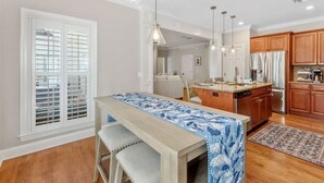 A modern kitchen with wooden cabinets, a central island, and pendant lighting. - Serene Smart Home, Big Backyard, PET FRIENDLY! (Tallahassee)