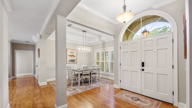 A spacious hallway with hardwood floors, white walls, and a dining area with a table and chairs. - Serene Smart Home, Big Backyard, PET FRIENDLY! (Tallahassee)