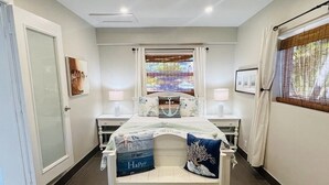 A bedroom with a bed, bedside tables, a window with curtains, a door, and a rug.