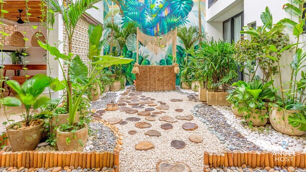 A tropical garden pathway with potted plants and a decorative wall mural. - Zamia Hotel Boutique (Playa del Carmen)
