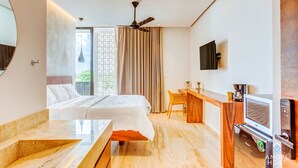 A modern hotel room with a bed, a desk with a TV, a coffee maker, and a view of greenery outside. - Zamia Hotel Boutique (Playa del Carmen)