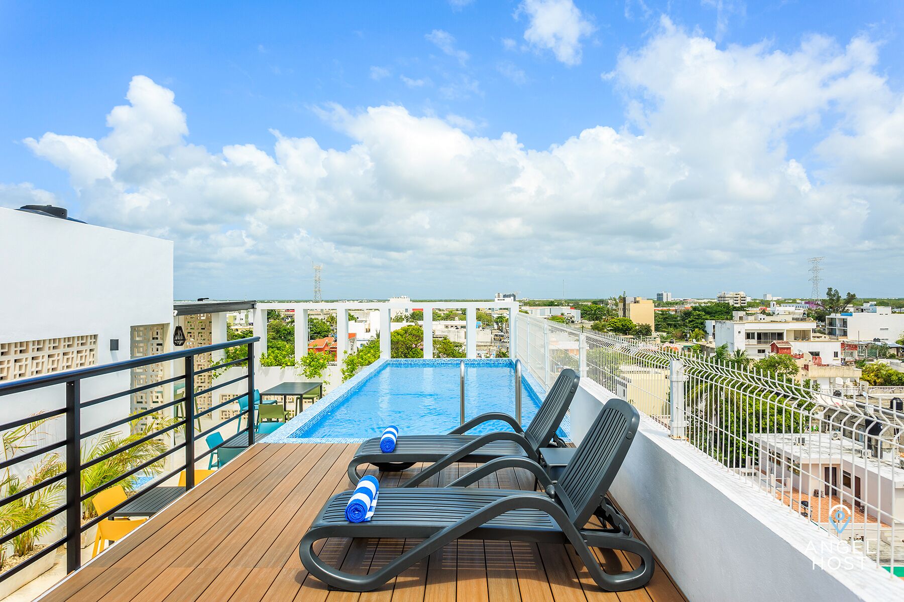 A rooftop pool with lounge chairs and a wooden deck.