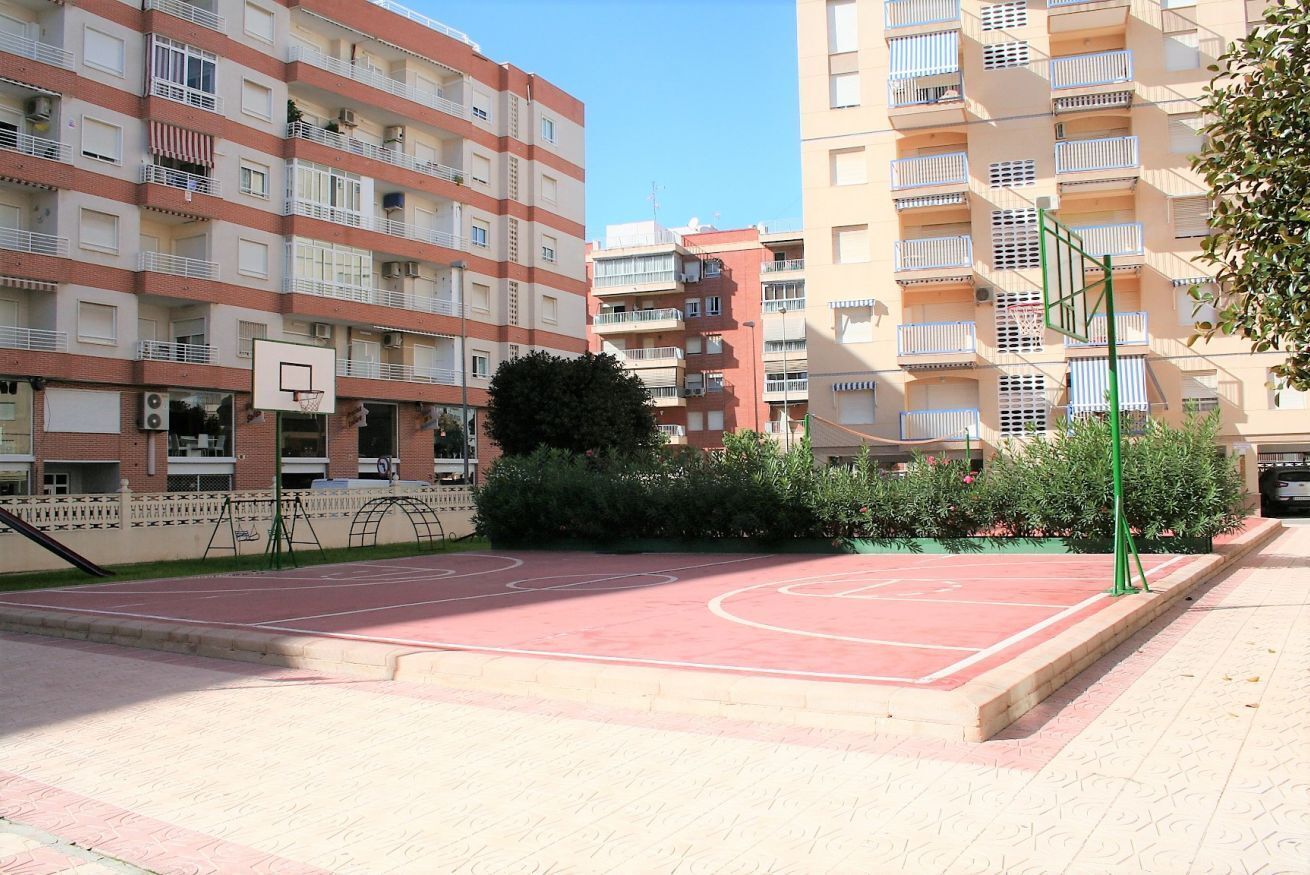 A basketball court surrounded by apartment buildings with balconies.