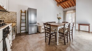 Eine Küche mit Holzboden, einem Esstisch mit Stühlen, einem Kühlschrank und einem Herd.