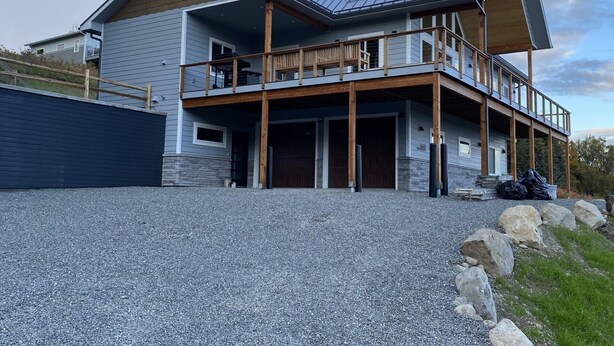 A two-story house with a balcony, a garage, and a stone foundation. - Incredible views in Homer, AK, first floor 2BR/1BA, kitchen, pet friendly (Homer)