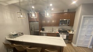 A modern kitchen with a large island, bar stools, stainless steel appliances, and wooden cabinets. - Incredible views in Homer, AK, first floor 2BR/1BA, kitchen, pet friendly (Homer)