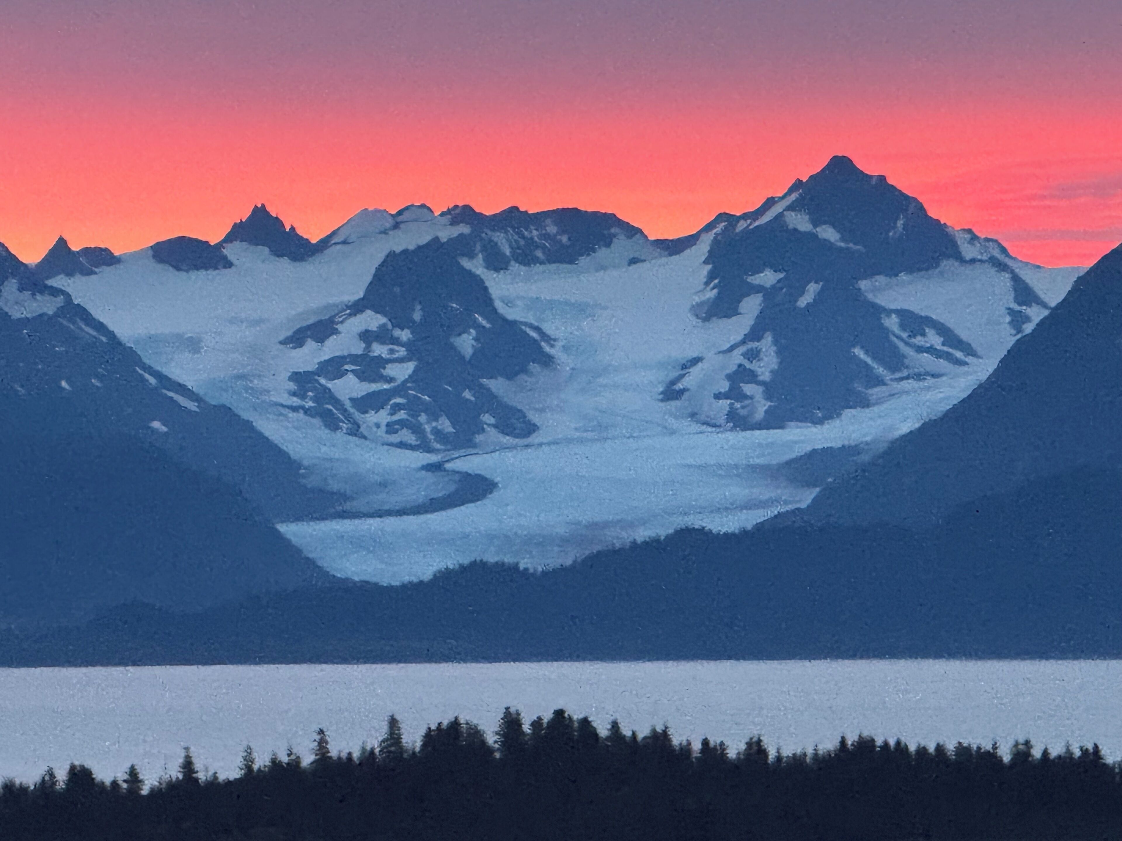 A mountain landscape with snow-covered peaks and a glacier.