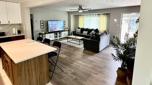 A spacious living area with a kitchen, a dining table, and a sofa. - Siesta Beach Getaway - Minutes to Beach, Shops, Dining (Sarasota)