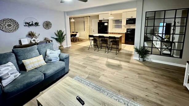 A modern living room with a sofa, coffee table, and a ceiling fan. - Siesta Beach Getaway - Minutes to Beach, Shops, Dining (Sarasota)