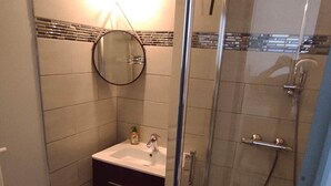 A bathroom with a glass shower enclosure, a sink with a mirror, and a towel rack. - Gîte Indépendant à la Campagne (Couffy)