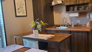 A compact kitchen with wooden cabinets, a built-in sink, and a dining area with a table set for two. - Dog friendly peaceful retreat for 2 (Concho)